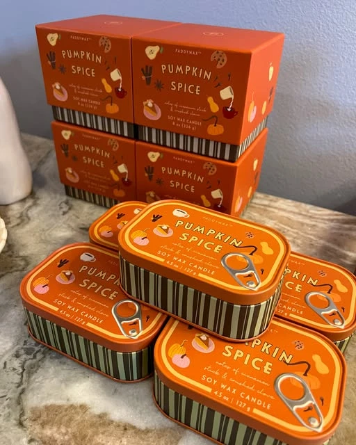Orange pumpkin spice candle tins displayed on a tabletop