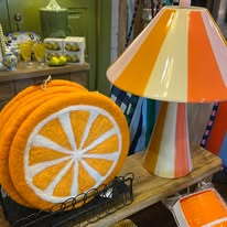 An orange slice-shaped cushion and striped lamp in a home display
